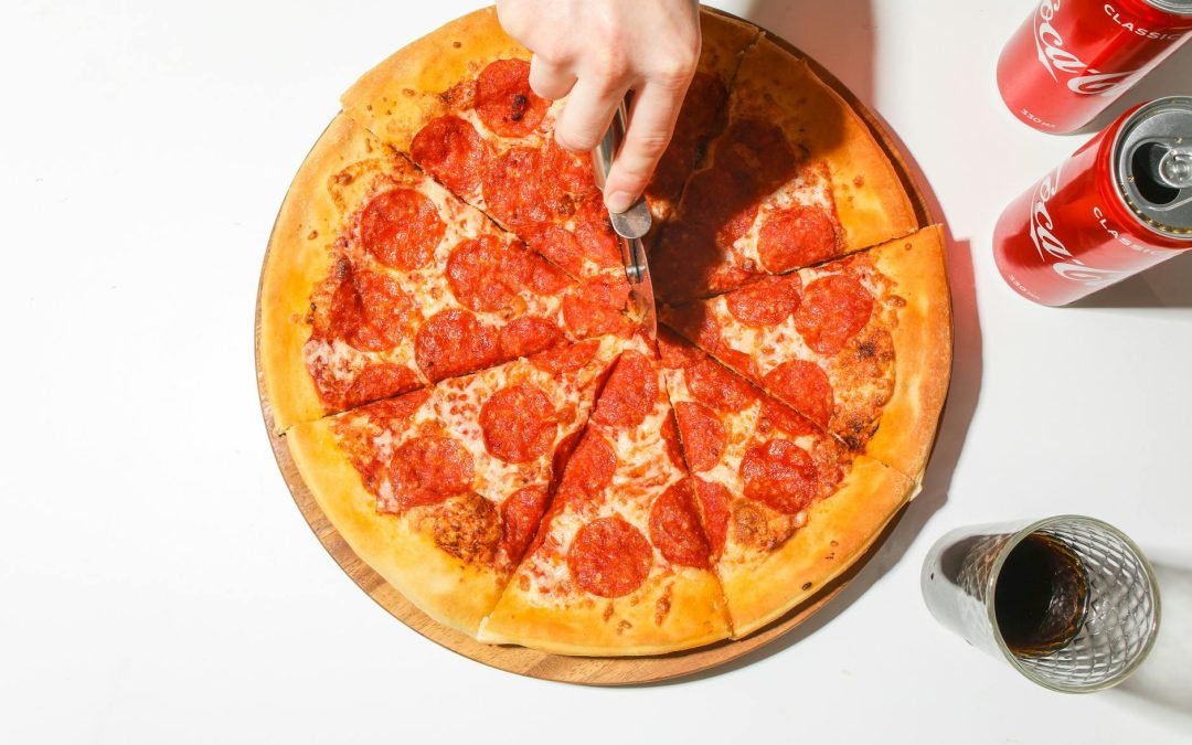 Person Slicing A Pizza With A Pizza Cutter