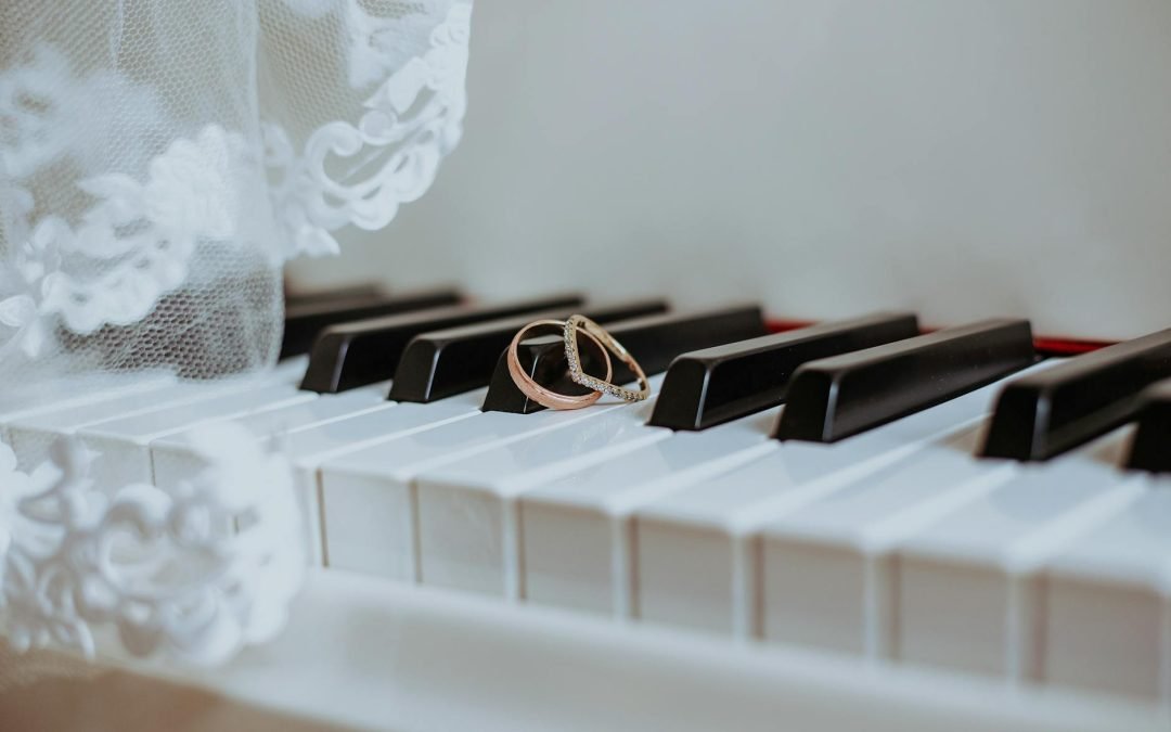 Golden rings on piano keyboard under veil with ornament during festive event in daytime